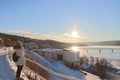 Rear view of man standing on snow against sky during winter