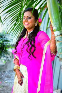 Portrait of smiling young woman standing on pink outdoors