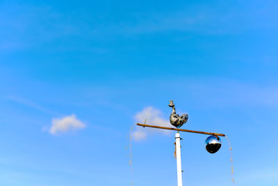 Low angle view of weather vane against blue sky