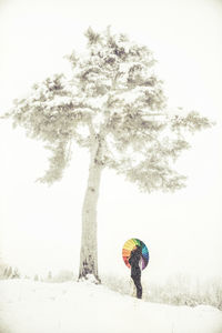 Woman on snow covered field against sky