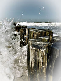 Close-up of ice splashing on wooden post in sea