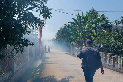 Rear view of man walking on footpath against sky