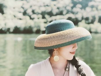 Portrait of woman wearing hat against water