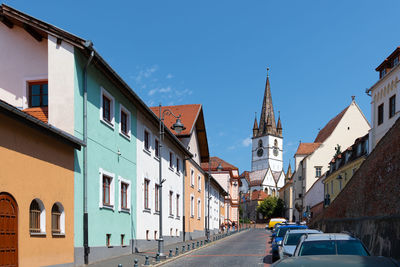 Cars on street against clear blue sky