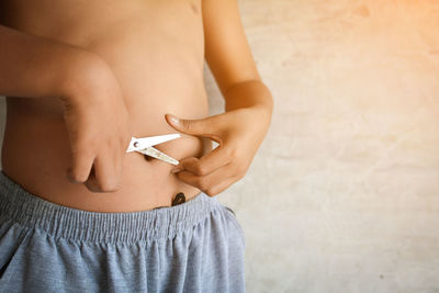 Midsection of boy cutting belly with scissors