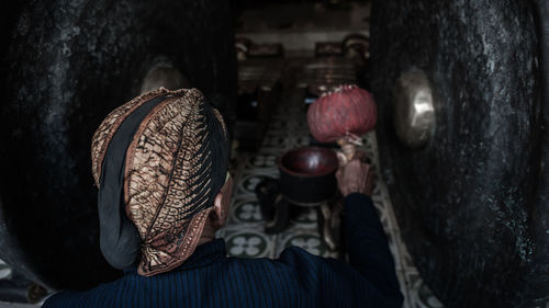 Rear view of man hitting gong in temple