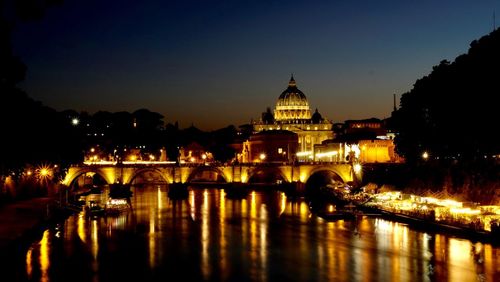 Reflection of illuminated arch bridge over river at night