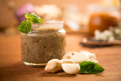 Close-up of garlic paste in jar by food on wooden table