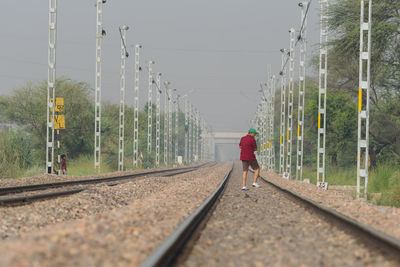 Rear view of man walking on railroad track