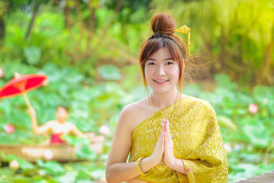 Portrait of smiling woman with clasped hand outdoors