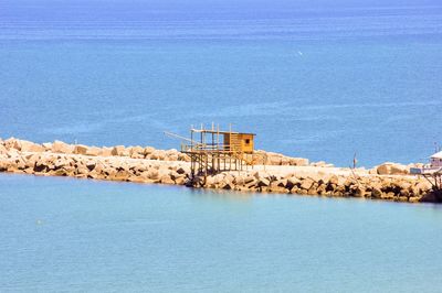 Built structure by sea against blue sky