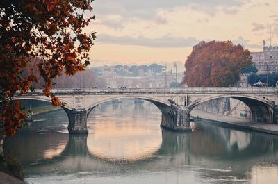 Bridge over river in city against sky