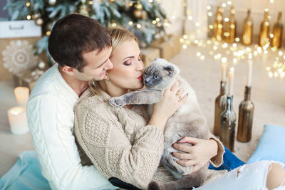 Couple embracing with cat sitting at home