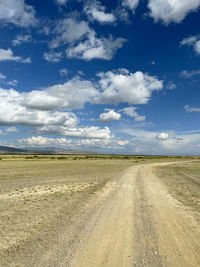 Dirt road along landscape against sky