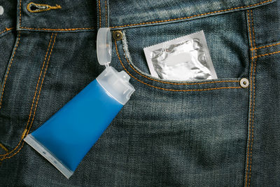 High angle view of condom and tube on jeans