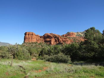 Rock formations on landscape against clear blue sky