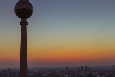 Communications tower in city at sunset