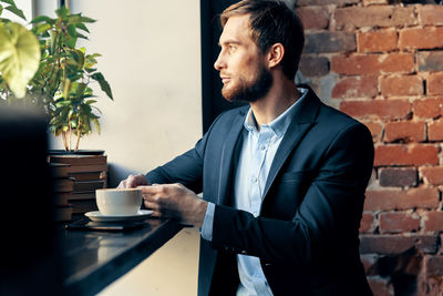 Man and coffee cup against wall