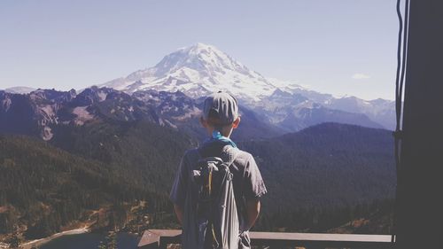 Rear view of man standing on mountain against sky