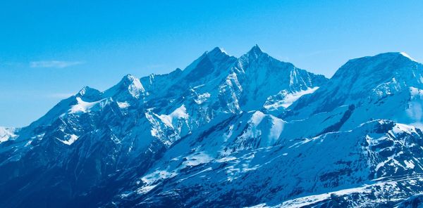 Scenic view of snowcapped mountains against clear blue sky