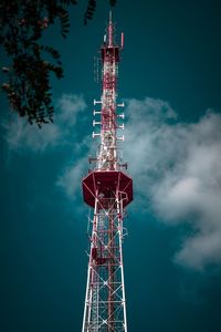 Low angle view of communications tower against cloudy sky