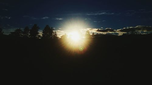 Sun shining through silhouette trees against sky during sunset