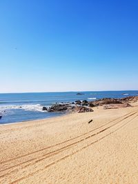 Scenic view of beach against clear blue sky