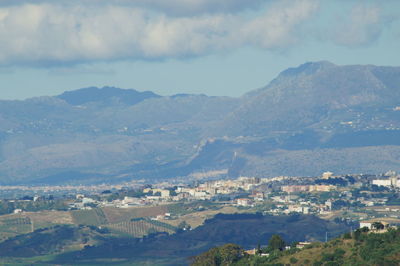 Aerial view of townscape and mountains against sky