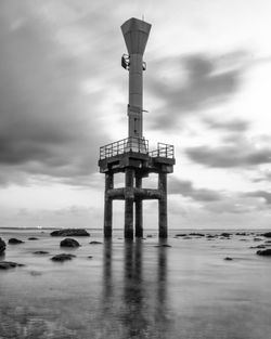 Cross tower on sea shore against sky
