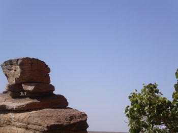 Heap of rocks with tree against clear sky