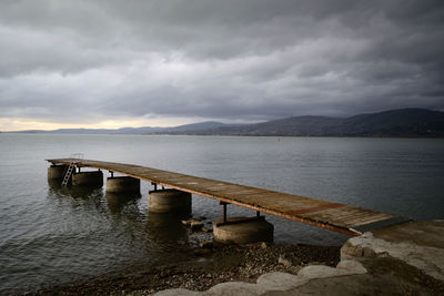 Bridge over river against cloudy sky