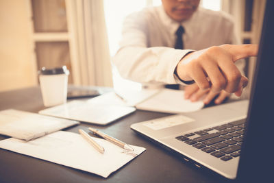 Midsection of man using laptop on table