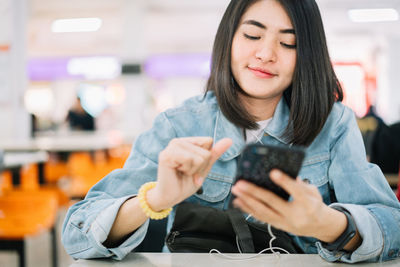 Mid adult woman looking at camera while sitting on mobile phone