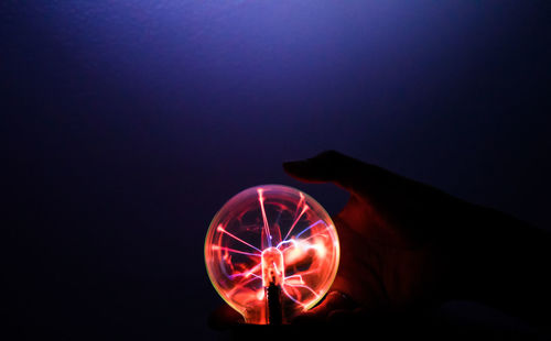 Hand holding illuminated light bulb at night