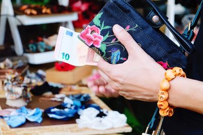 Cropped hand of woman holding purse and paper currency in market