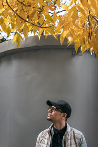 Man looking away while standing against wall