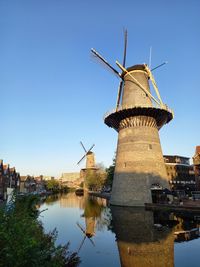 Traditional windmill by river against sky