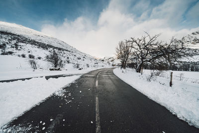 Road amidst snow covered landscape against sky