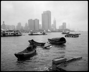 Boats moored in sea against cityscape