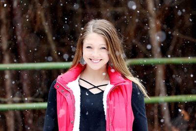 Portrait of smiling girl standing outdoors during snowfall