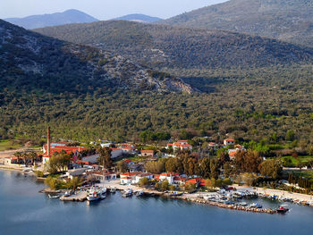 Sailboats moored in harbour by buildings and mountains