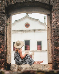 Rear view of woman looking through window