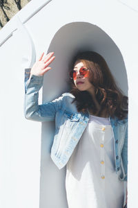 Young woman wearing sunglasses standing against car
