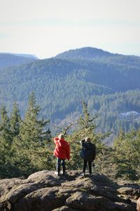 Rear view of boys standing on rock against tree mountain