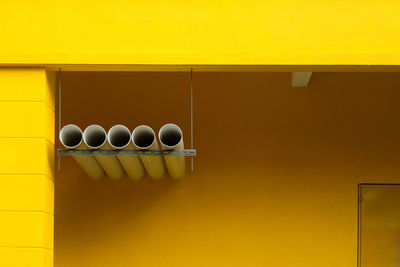 Row of exhaust duct against a yellow building