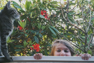 Close-up of girl with cat by plants