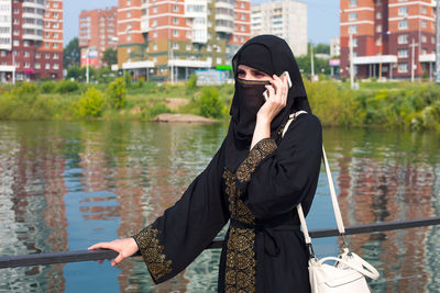 A muslim woman in national clothes with a phone in her hands against the background 