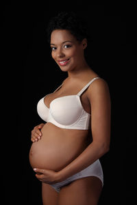 Portrait of a smiling young woman against black background