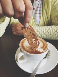 Woman dipping biscuit into coffee cup