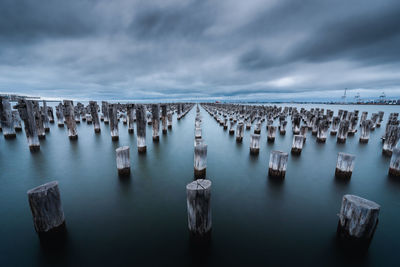 Panoramic view of wooden posts in sea against sky